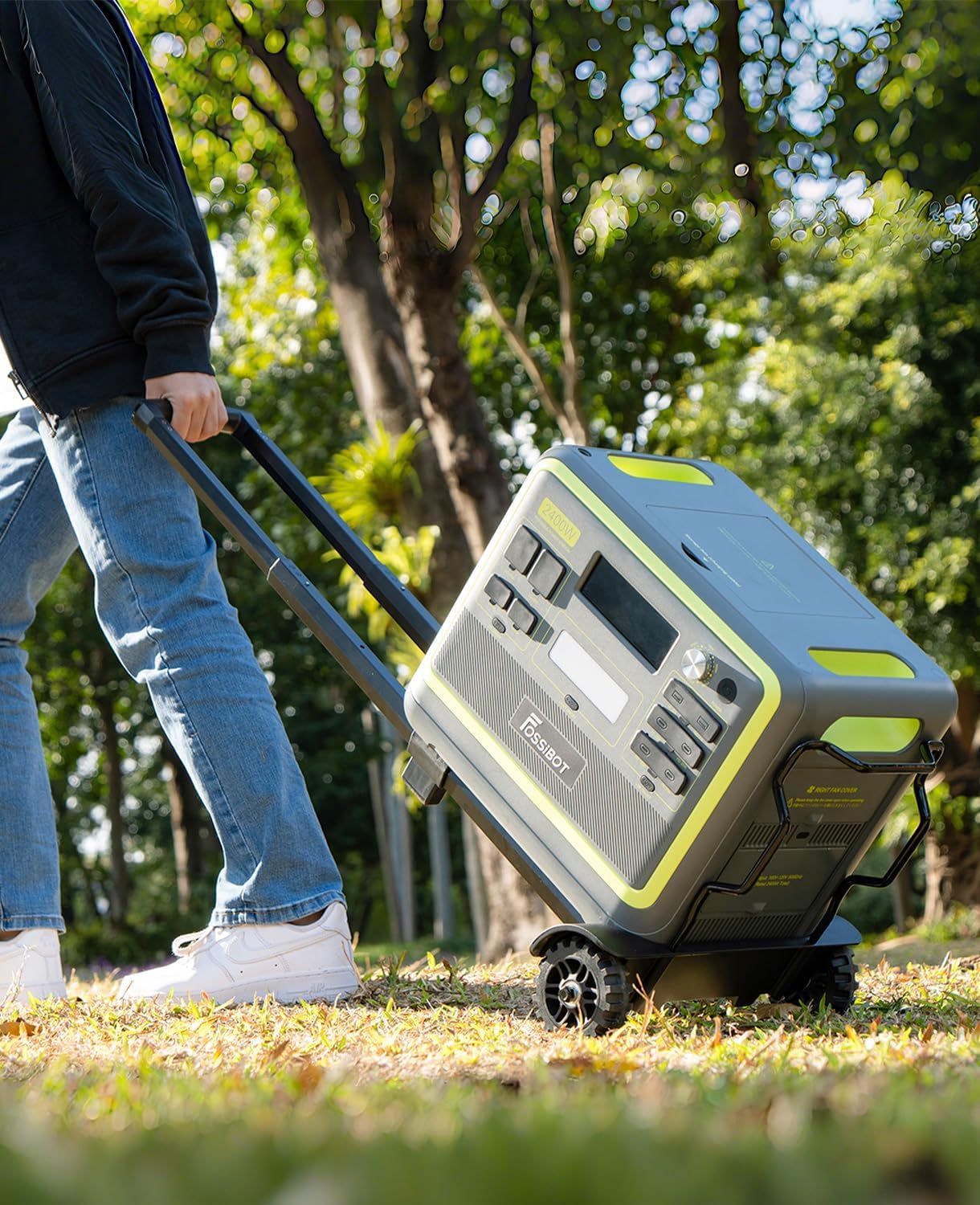 Person pushing a portable power station on wheels through a park.